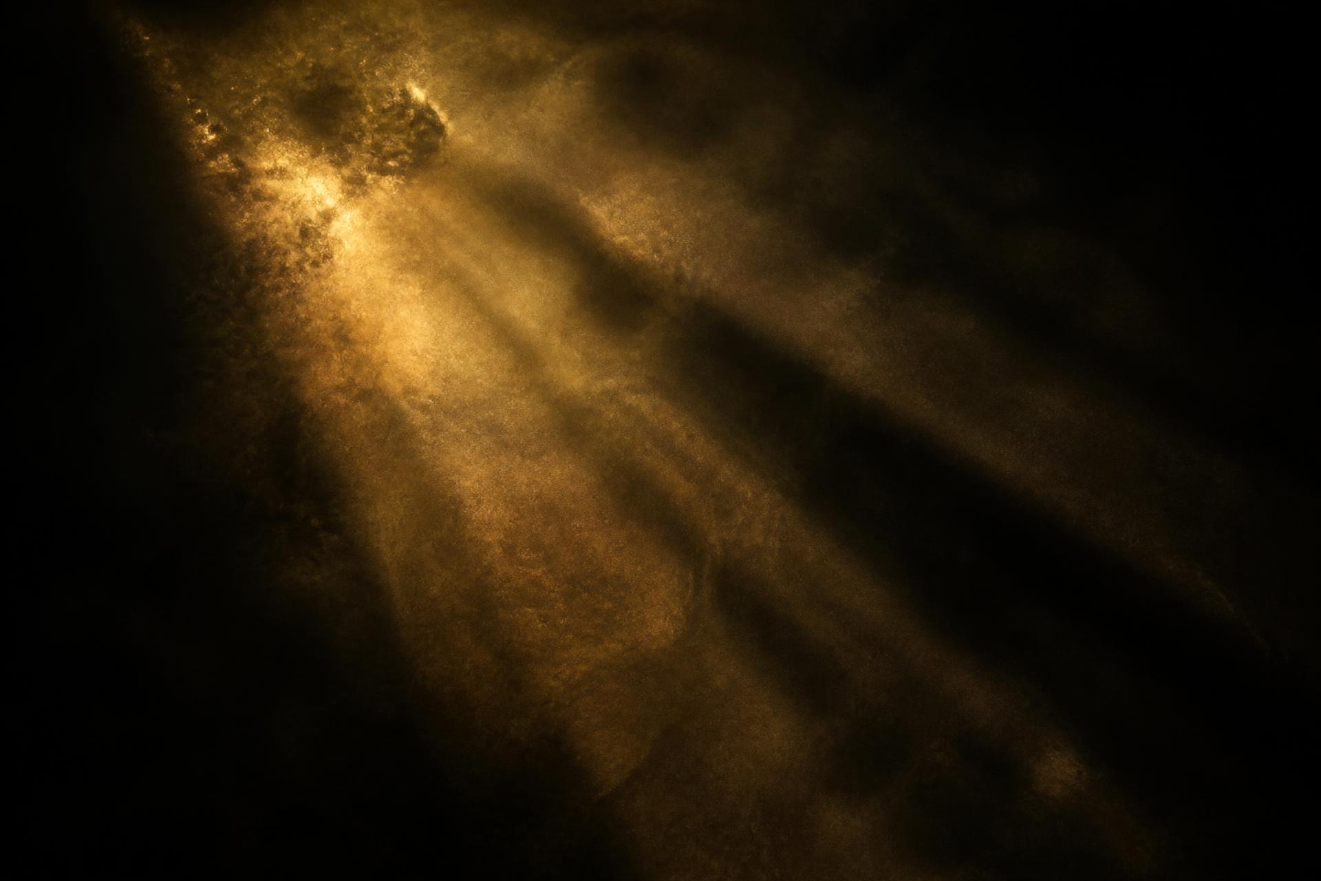 Golden light rays breaking through dark mist